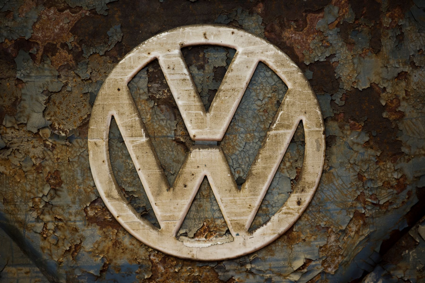 A worn and rusted Volkswagen VW logo on a T1 van built in 1951