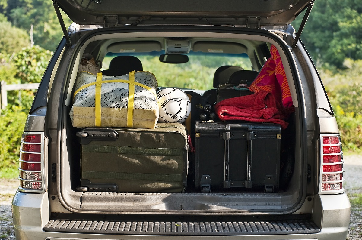 The rear cargo space of an SUV is shown packed full with items