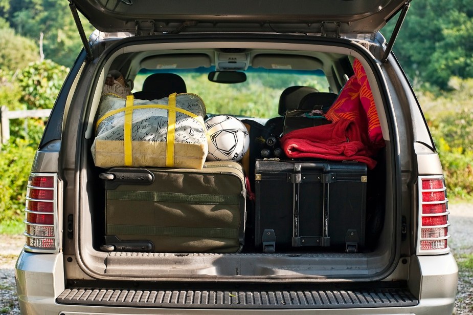 The rear cargo space of an SUV is shown packed full with items