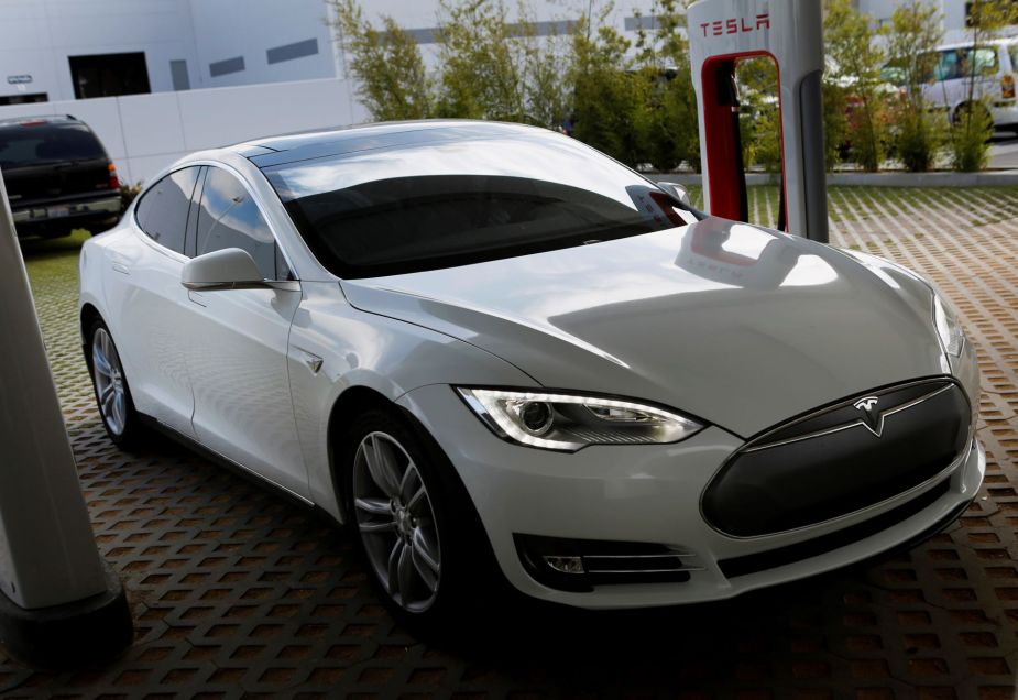 A used 2013 Tesla Model S all-electric full-size luxury sedan at a charging station