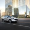 A white 2022 Ford Escape compact SUV driving past a reflective skyscraper