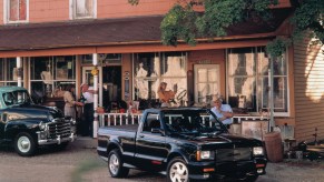 Black 1991 GMC Syclone pickup truck parked in front of an old building.