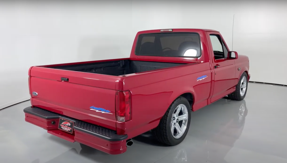 The bed of a 1994 Red Ford  F-150 SVT Lightning muscle truck parked in a showroom, a white wall visible in the background.