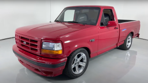 The grille of a Red Ford F-150 SVT Lightning muscle truck parked in a showroom, a white wall visible in the background.