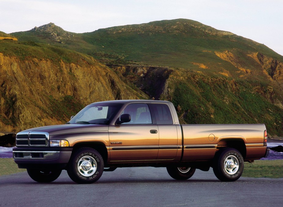 Beige 2000 Dodge Ram 2nd Gen truck with a Cummins diesel engine parked in front of a green mountain for a publicity photo.