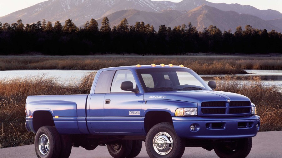 Blue 2001 Dodge Ram pickup truck with a 2nd Gen Cummins engine parked by a lake with mountains visible in the background.