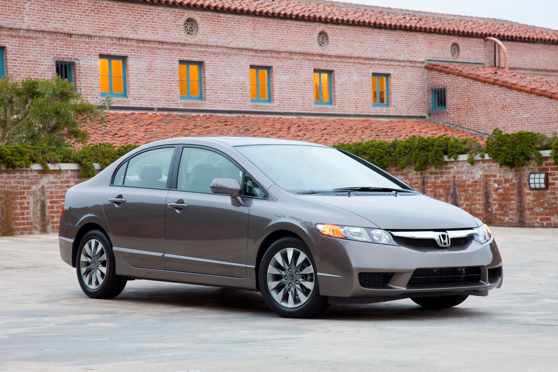 A gray 2009 Honda Civic EX-L compact sedan model parked outside of a red brick building
