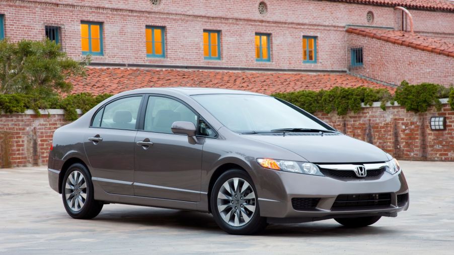 A gray 2009 Honda Civic EX-L compact sedan model parked outside of a red brick building