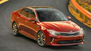 A red 2016 Kia Optima driving on a highway.