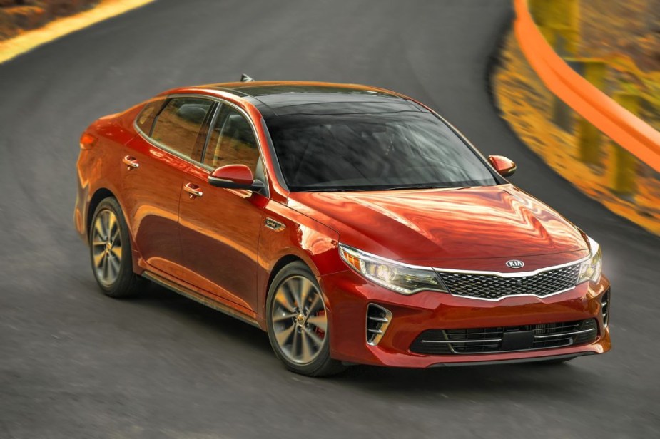A red 2016 Kia Optima driving on a highway.