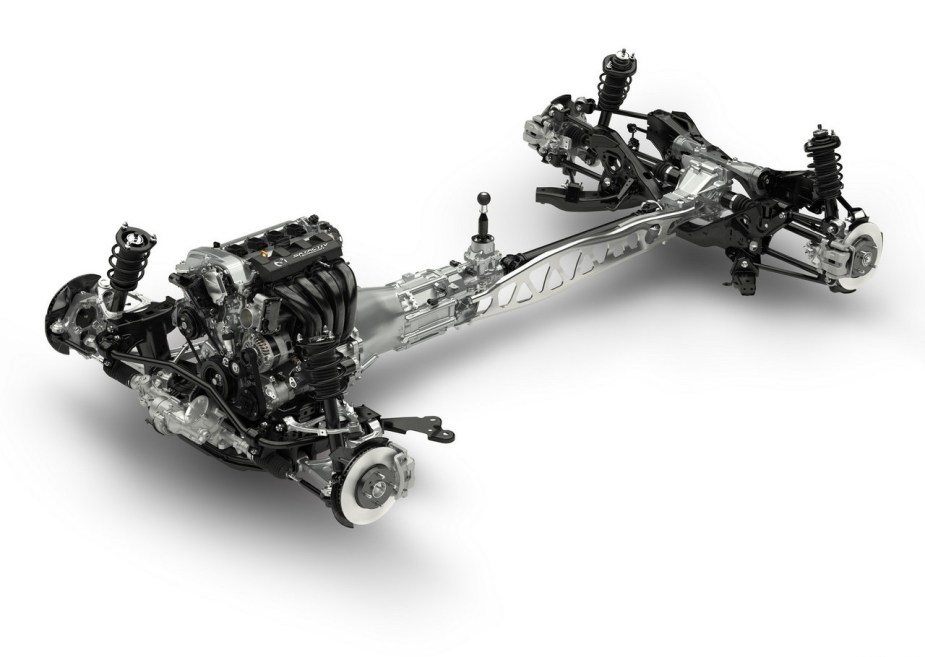 The isolated engine, transmission, axles, and chassis of a MX-5 Mazda Miata, set against a white background.
