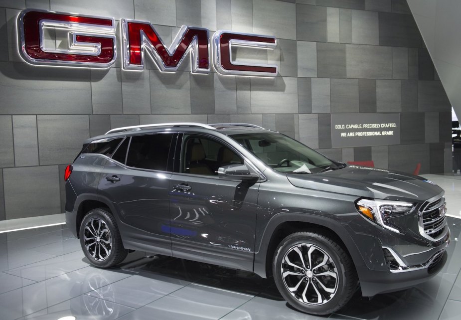 2017 GMC Terrain parked indoors in front of the GMC logo, which recently went through a GMC Terrain headlight recall. 