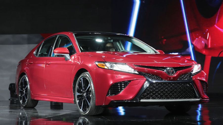 A red 2018 Toyota Camry on display at an auto show.