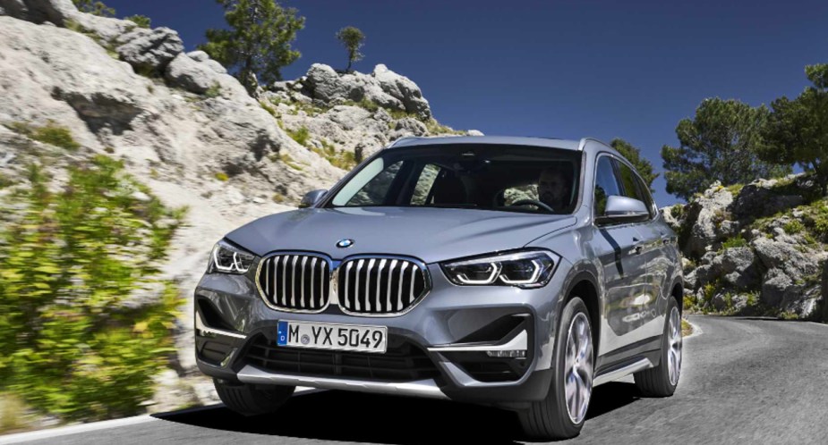 A gray 2019 BMW X1 small luxury SUV is driving on the road. 