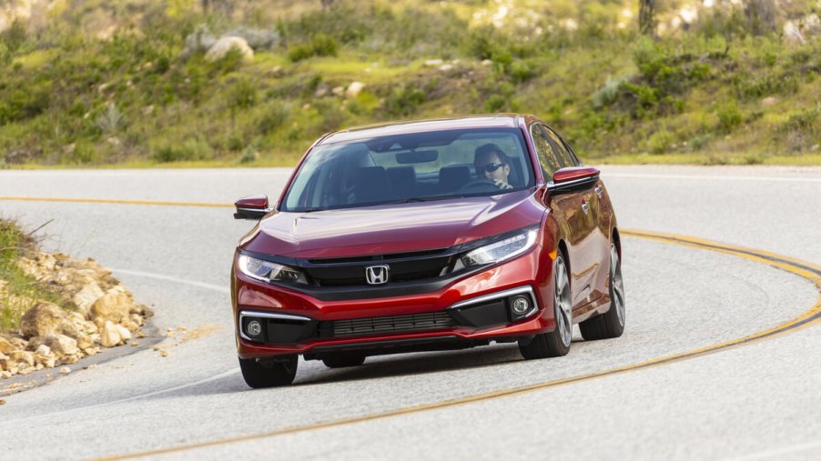 A red 2019 Honda Civic Sedan takes a corner on a country road.