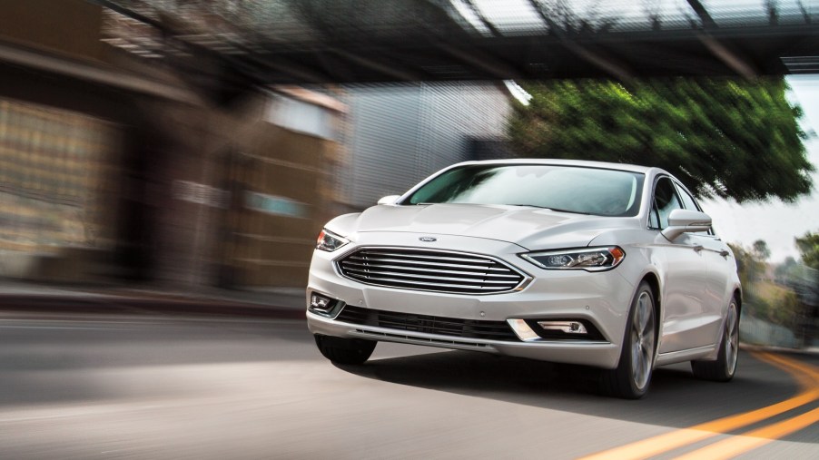 The now-discontinued Ford car, the Fusion Hybrid, blasts down an urban road.