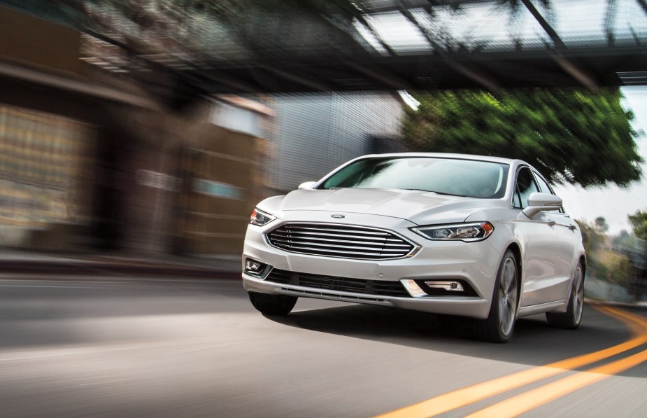 The now-discontinued Ford car, the Fusion Hybrid, blasts down an urban road. 