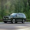 2022 Lincoln Navigator Manhattan Green Black Label full-size luxury SUV driving on a forest highway