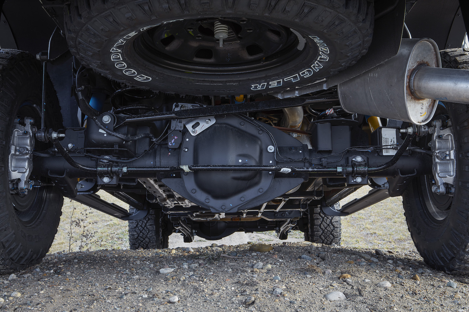 The drivetrain of a 4WD Ram 2500 Power Wagon pickup truck parked on a gravel road, its spare tire visible.