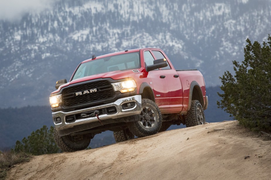 A red 2022 Ram 2500 power wagon pickup truck parked on a sandy off-road trail, a snowy mountain visible in the background.