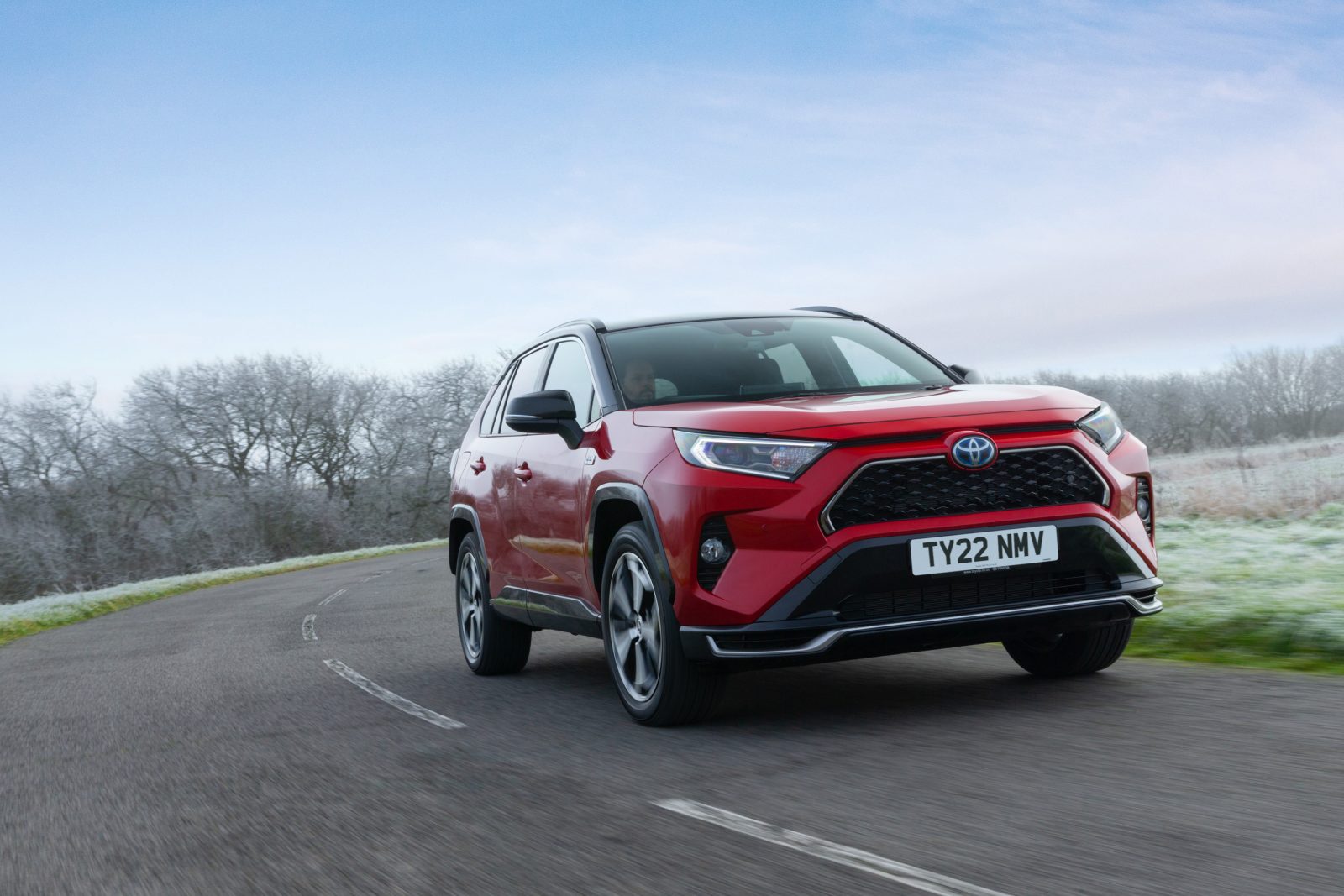 A red 2022 Toyota RAV4 Hybrid driving on the road