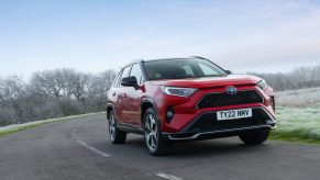 A red 2022 Toyota RAV4 Hybrid driving on the road