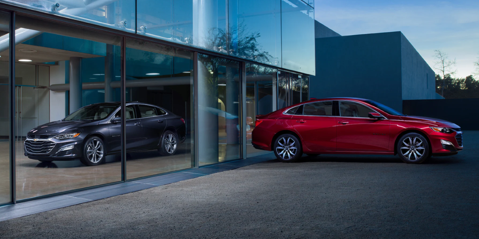 2023 Chevrolet Malibu midsize sedan models in gray and red separated by glass panels