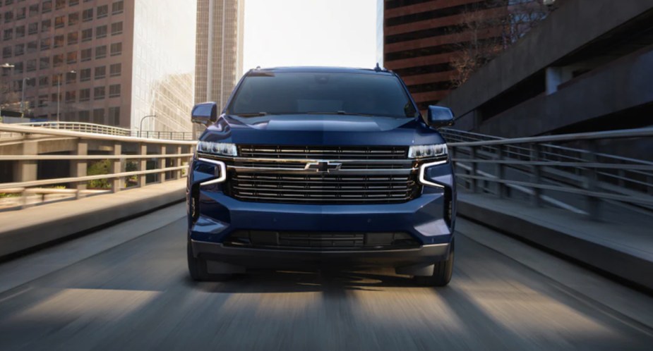 A blue 2023 Chevrolet Tahoe full-size SUV is driving on the road. 