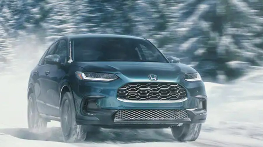 A green 2023 Honda HR-V subcompact SUV is driving in the snow.