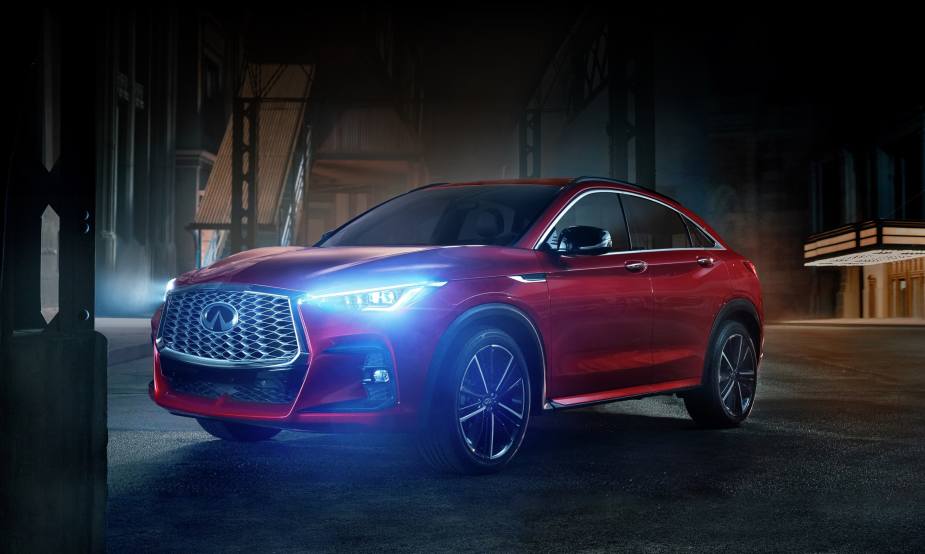 A red 2023 Infiniti QX55 is parked with headlights on at night. Is it underrated or overpriced?