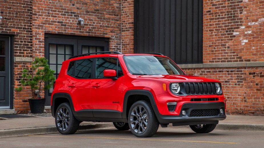 Advertising photo of a red Jeep Renegade crossover SUV parked in a lot, a brick wall visible in the background.