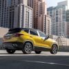 A yellow 2023 Kia Seltos subcompact SUV model parked on a rooftop shaded by skyscrapers