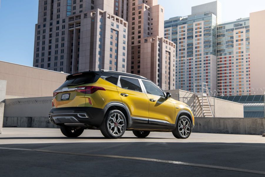 A yellow 2023 Kia Seltos subcompact SUV model parked on a rooftop shaded by skyscrapers