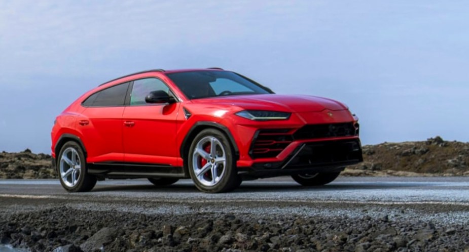 A red 2023 Lamborghini Urus is parked off-road. 