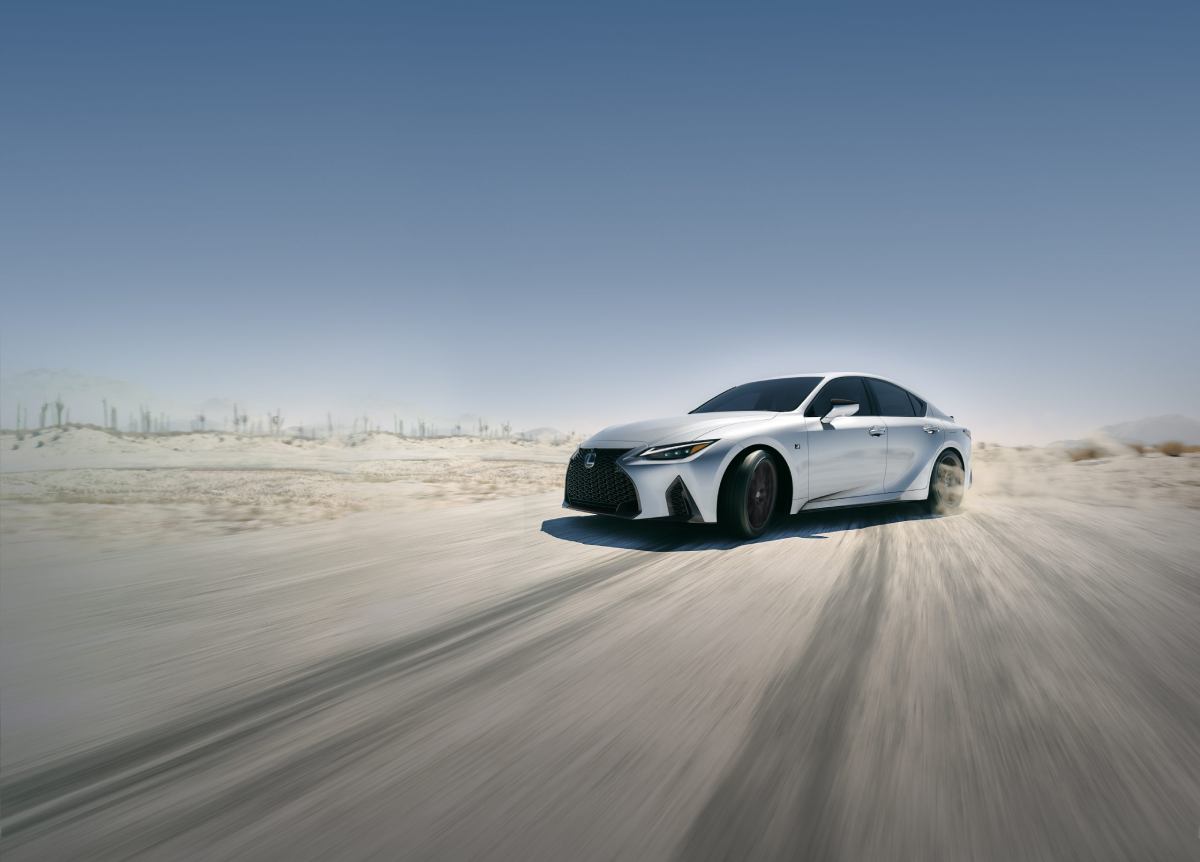 A 2023 Lexus IS driving on a dusty road.