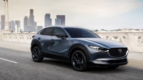 A blue 2023 Mazda CX-30 subcompact SUV is driving on the road.