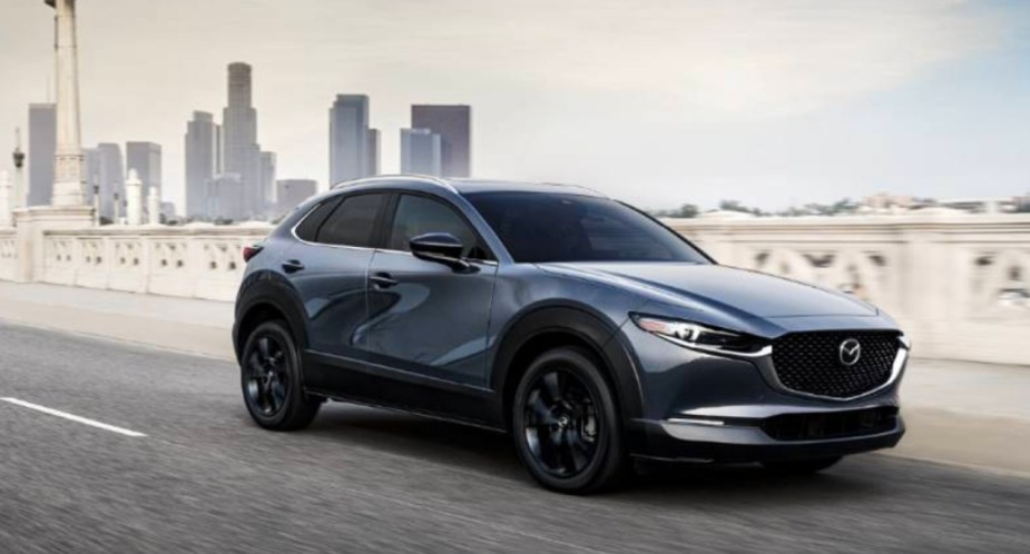 A blue 2023 Mazda CX-30 subcompact SUV is driving on the road. 