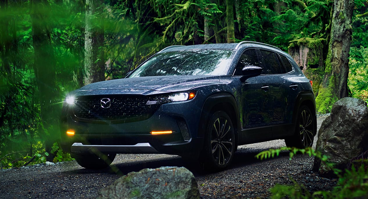 A blue 2023 Mazda CX-50 small SUV is driving off-road.