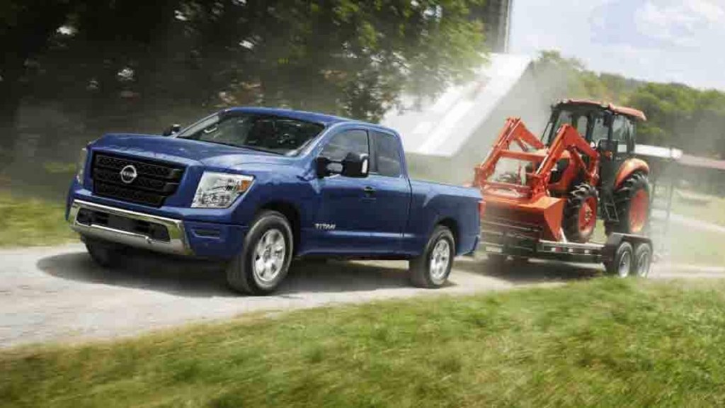 2023 Nissan Titan Pulling a Trailer Loaded with a Digger at a Farm