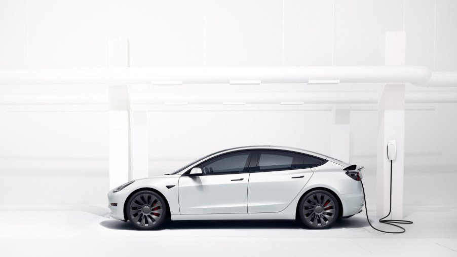 A Tesla Model 3 rental car charges in a white room.