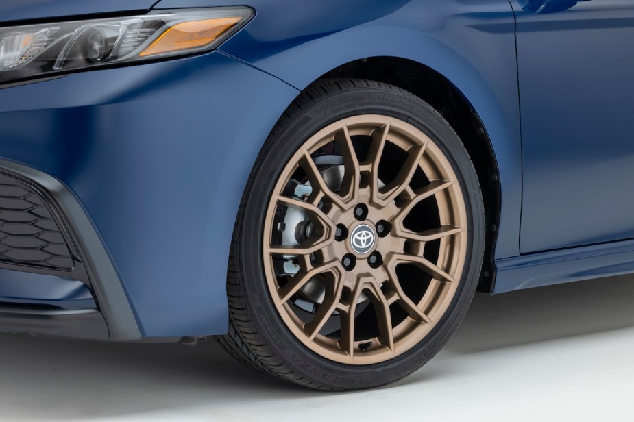 A blue 2023 Toyota Camry with sport tires and upgraded TRD wheels in bronze.