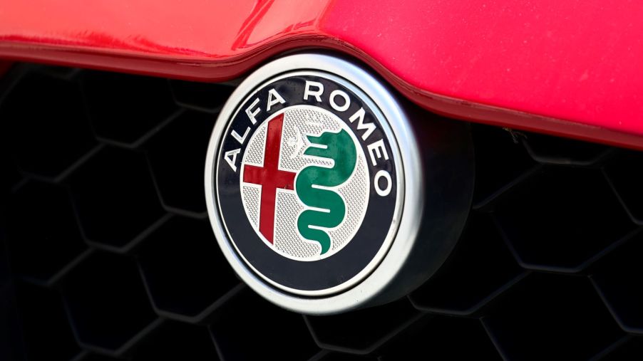 The Alfa Romeo logo on the grille and under the hood of a red model