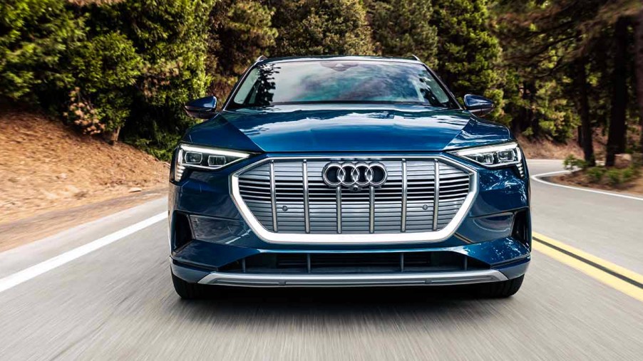 A blue 2023 Audi E Tron is driving on the road.