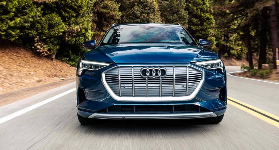 A blue 2023 Audi E-Tron is driving on the road. 