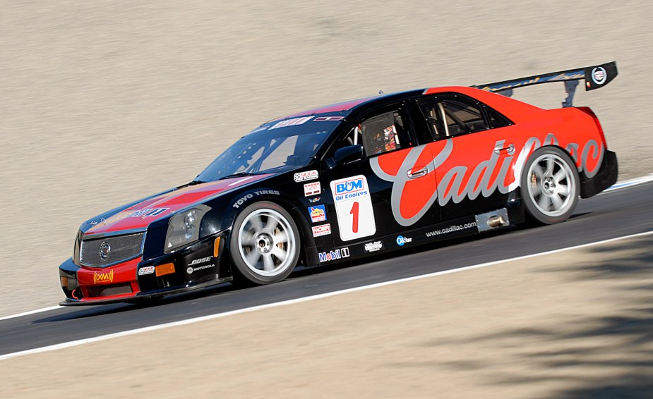 Team Cadillac's black and read CTS-V race car laps a track at high speeds.