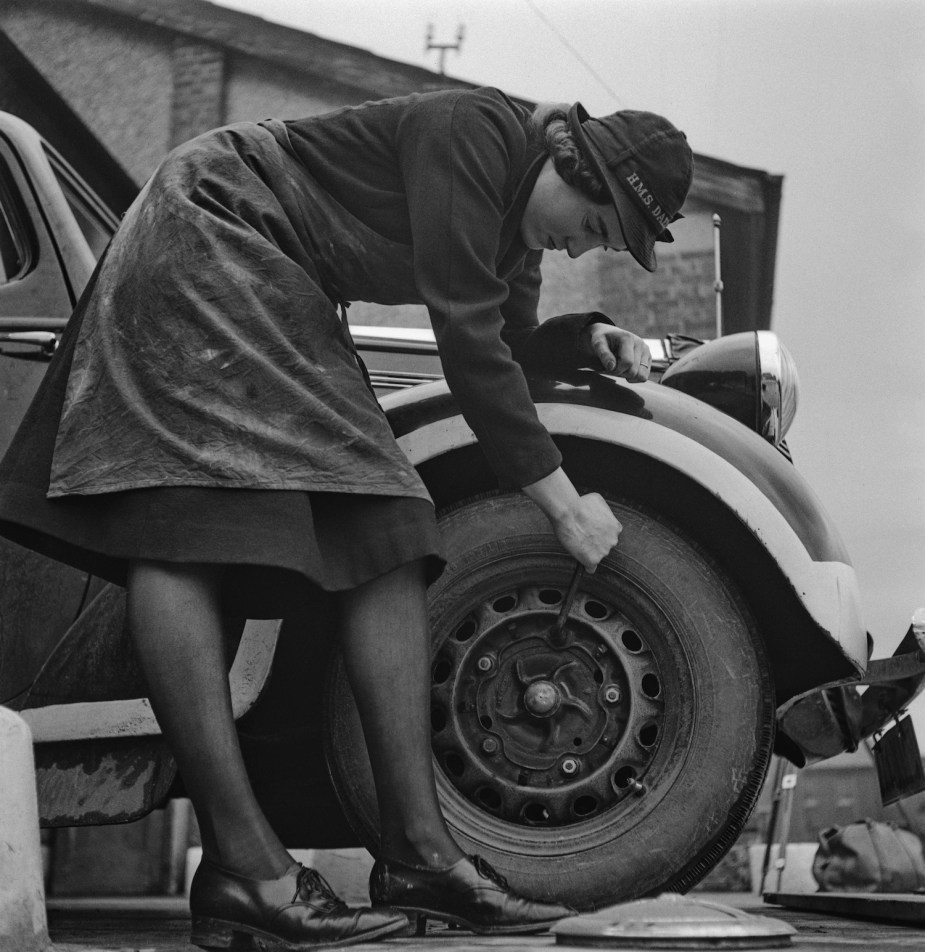 A mechanic in the British Royal Naval Service changes the tire on a staff car in 1941.