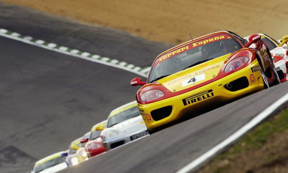 Red and Yellow Ferrari 360 Modena supercar leading a pack around a race track.