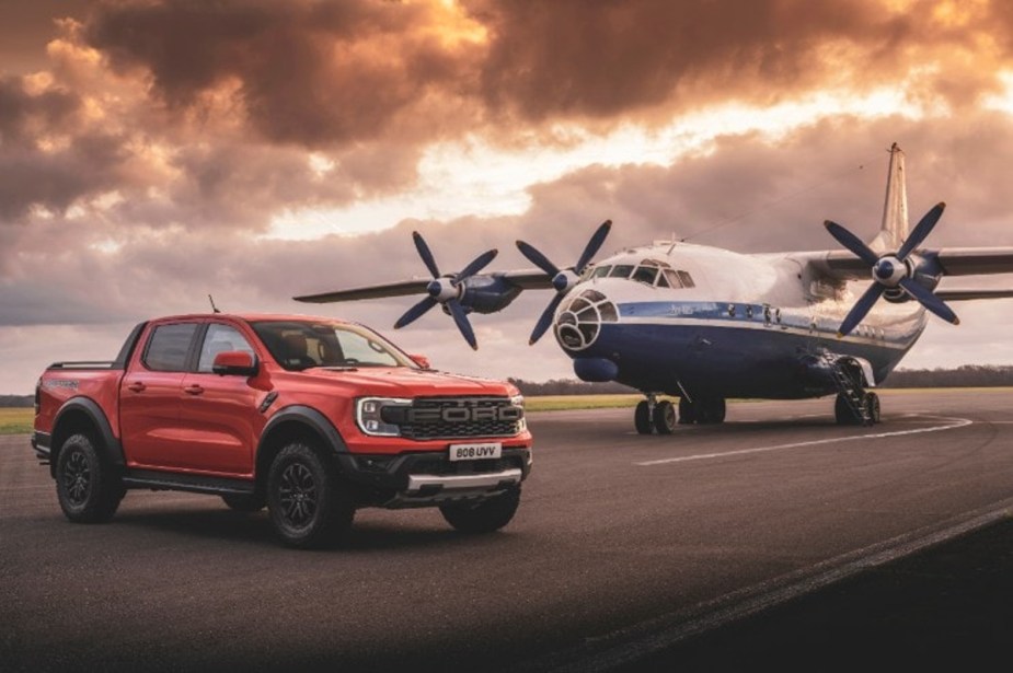 A Ford Ranger Raptor sits in front of an airplane.