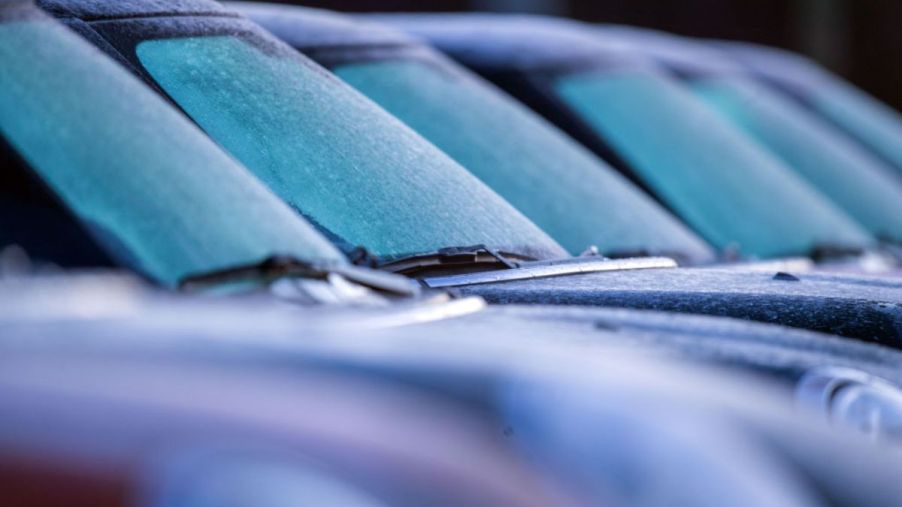 Cars in a parking lot with icy windshields.