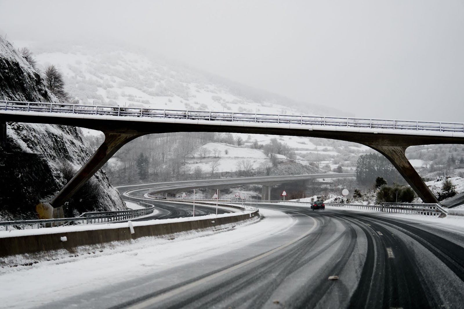 A snow-covered road under a bridge